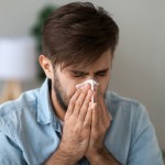 Sick man got flu grippe or allergy sneezing in handkerchief blowing wiping running nose, ill allergic guy caught cold coughing in tissue, having seasonal allergy symptoms, hay fever treatment concept